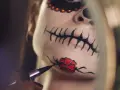 Nahaufnahme eines Gesichts mit Totenkopf-Make-up, das mit einem Pinsel bemalt wird.