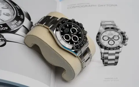 Luxuriöse Rolex Daytona Uhr auf einem Kissen vor einem Buch mit Uhrenabbildungen.