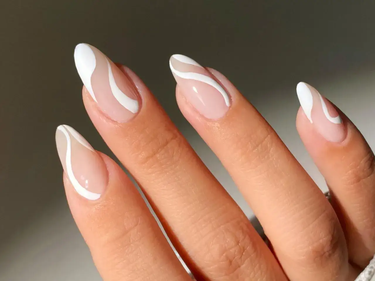 Elegantes gel nagel design mit weißen Wellenlinien auf nacktem Untergrund.